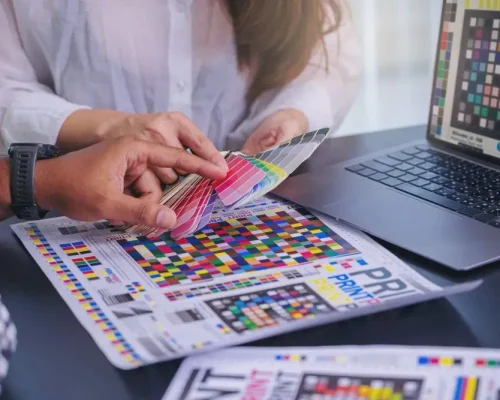 Zwei Personen prüfen Farbmuster am Schreibtisch, symbolisch für die Druck‑ und Grafikbranche.